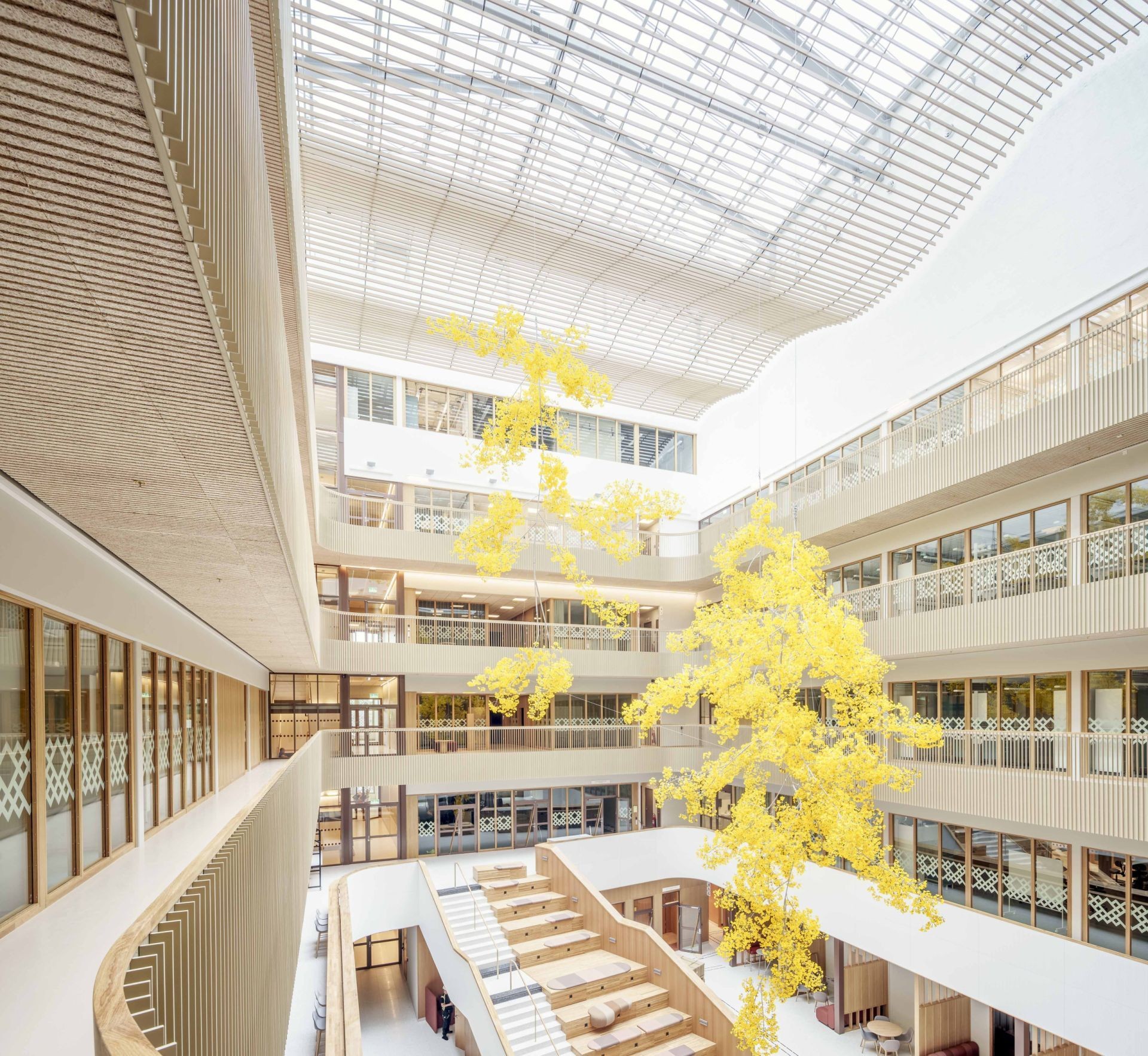 Modern atrium with large skylight and bright yellow tree sculpture suspended in the center.